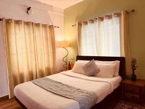 a bedroom with a bed with white sheets and a window at Casa Serenity in Ooty