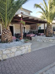 a resort with palm trees and a patio at Apartmani Goga - Molat 6 in Molat
