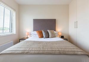 a white bedroom with a large bed with two lamps at House of Fisher - Athena Court in Maidenhead
