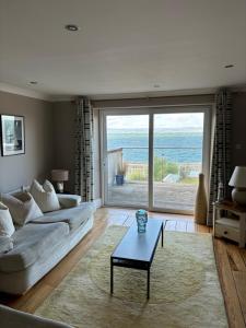 a living room with a couch and a table at Splash Cottage beach house with Sea lapping Garden in Bangor