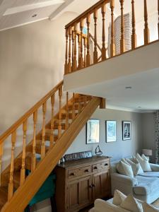 a living room with a staircase and a couch at Splash Cottage beach house with Sea lapping Garden in Bangor