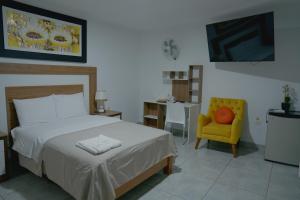 a bedroom with a bed and a yellow chair at Hotel San Martín in San Juan de Marcona +91 photos