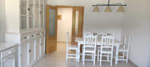 a kitchen with a table and white chairs at Apartamento EL RIO in Biescas