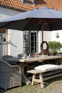 een houten tafel met een parasol op een patio bij B&B Hoeve de Steenoven in Damme