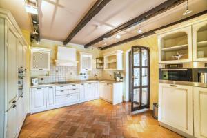 a kitchen with white cabinets and a wooden floor at Villa Romana by Rent Istria in Višnjan