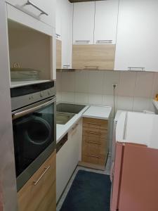 a kitchen with white cabinets and a black oven at Dimitra Stan na dan in Šabac