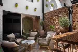 un patio con sillas, mesas y una pared de piedra. en Casa Azalia - Marbella Old Town, en Marbella