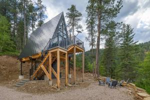 a building with a roof on top of a forest at Pines Cabin- A-Frame- Hot Tub-Sauna- Firepit in Woodville
