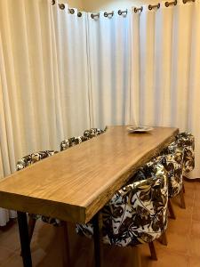 a wooden table with chairs in front of a curtain at Allamanda House Meru in Arusha