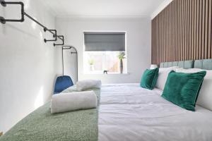 a bedroom with a large white bed with green pillows at Rayleigh Weir - Luxury 3 bedroom house with games room in Rayleigh
