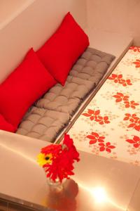Una cama con almohadas rojas y un jarrón con flores sobre una mesa en Studio Apartment Centre Historique en Arlés