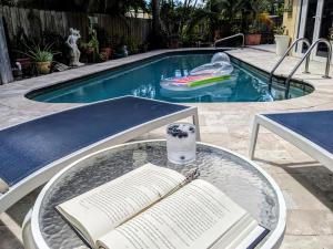a glass table with an open book on a table with a swimming pool at Tropical Escape with Private Heated Pool in North Palm Beach