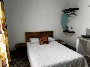 a bedroom with a white bed with a wooden headboard at Rosita in Taxco de Alarcón