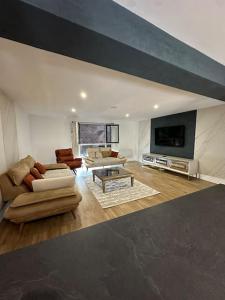 a large living room with couches and a tv at Sublime maison de 2 étages avec cour in Chilly-Mazarin