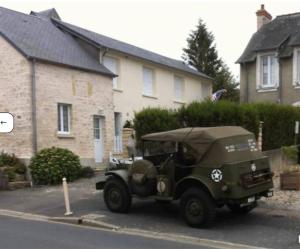 an old military jeep parked in a parking lot at Maison T3 avec jardin centre-ville in Vierville-sur-Mer