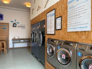 a laundry room with three washing machines and a sign at Porta 28 in Quinta do Anjo