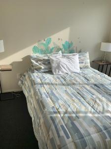 ein Schlafzimmer mit einem Bett mit einer Bettdecke und Kissen in der Unterkunft Peaceful Riverfront cottage in small northland town in Te Kopuru