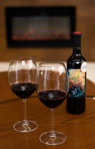 two glasses of red wine next to a bottle of wine at Casa em Tiradentes 14 pessoas in Tiradentes +31 photos