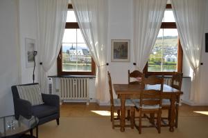 a dining room with a table and chairs and windows at Ferienwohnungen am Stadtpalais Fewo-Mosel in Bernkastel-Kues
