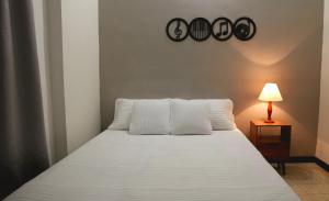 1 dormitorio con 1 cama blanca con 2 almohadas y lámpara en Cali te espera, en Cali