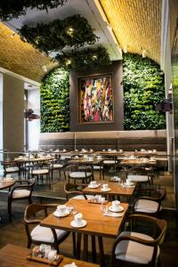 a restaurant with tables and chairs and plants on the wall at Prestige Hotel Budapest in Budapest