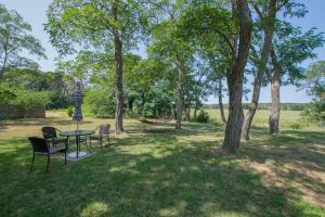 a table and chairs in a park with trees at Waterfront w views on Blackfish Creek in Wellfleet