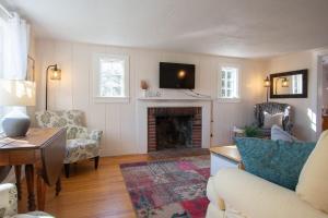 a living room with a fireplace and a tv at 15556 - Walk to Skaket Beach or Bike to Rail Trail w Outdoor Shower SUP Board Ping Pong Table in Orleans