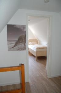クックスハーフェンにあるStrandhaus Deichvoigtのベッドルーム1室(ベッド1台付)が備わります。壁には絵画が飾られています。