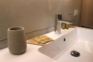 a bathroom sink with a faucet and a vase on it at Rustic Apartment -100mt from BerninaExpress in Tirano