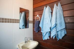 un bagno con asciugamani blu appesi a una parete di legno di Hostel Capricórnio Carcará a Caraguatatuba