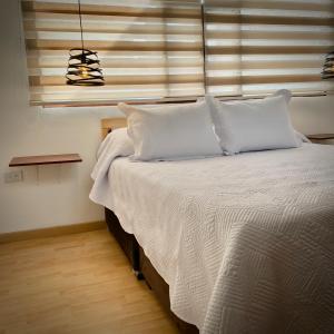 a bedroom with a bed with white sheets and a window at Apartaestudio Loft 201 - UE Home in Duitama