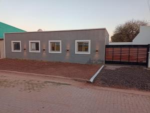 a gray house with white windows and a brick driveway at Cabañas Gadiel in San José de las Salinas