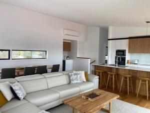 a living room with a white couch and a kitchen at Rusty's Ridge in Jindabyne
