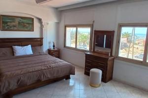 a bedroom with a bed and a desk and windows at Superbe Villa Avec Piscine & Belle Vue Sur Mer in Tamaris