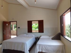 two beds in a room with white sheets at Pousada Biana Residence in Santo Amaro