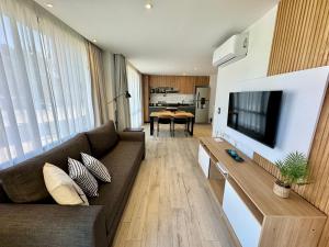 a living room with a couch and a flat screen tv at Departamento Moderno Premium con Piscina y Cochera in Pinamar +8 photos