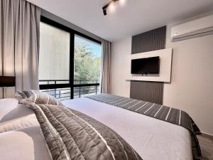 a bedroom with a bed and a large window at Departamento Moderno Premium con Piscina y Cochera in Pinamar