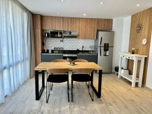 a kitchen with a wooden table with chairs and a refrigerator at Departamento Moderno Premium con Piscina y Cochera in Pinamar