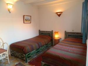 a bedroom with two beds and a chair and a lamp at Les Matins Bleus in Essaouira