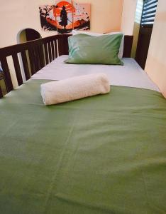 a bed with a green blanket and a pillow on it at The Eagle in Galle