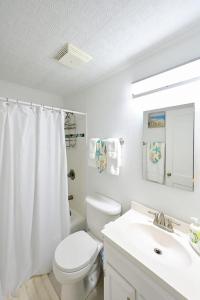 a white bathroom with a toilet and a sink at Charming Florida cottage in Largo