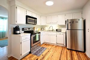 a kitchen with white cabinets and a stainless steel refrigerator at Charming Florida cottage in Largo +9 photos
