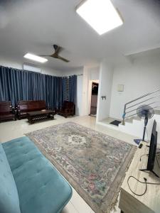 a living room with a blue couch and a large rug at KJ Homestay, BINTULU in Bintulu