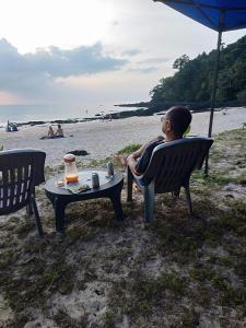 Eine Frau auf einem Stuhl am Strand in der Unterkunft Longbeach Bungalow Kohmook in Ko Mook + 14 Fotos