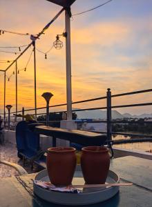 two cups on a plate on a table with the sunset at Whereabout Hostel Udaipur in Udaipur