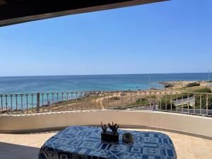 a table on a balcony with a view of the ocean at Attico Fronte Mare Salento in Torre San Giovanni Ugento