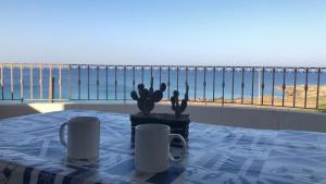 a table with two cups and a view of the ocean at Attico Fronte Mare Salento in Torre San Giovanni Ugento