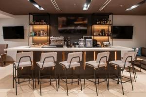a bar with stools around a counter in a room at Courtyard by Marriott San Salvador in San Salvador