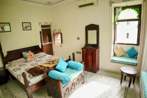 a bedroom with a bed with blue pillows at Whereabout Hostel Udaipur in Udaipur