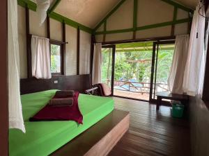 a green bed in a room with a window at Smile Bungalow Bottle Beach in Bottle Beach